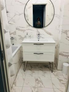 a white bathroom with a sink and a mirror at Bisou Elsa Apartment in Narva-Jõesuu