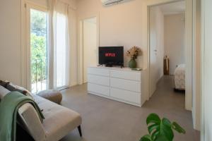 een woonkamer met een tv op een wit dressoir bij Casa del Moletto - 250mt from the sea in Lacona