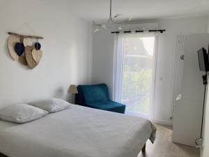 ein Schlafzimmer mit einem Bett, einem blauen Stuhl und einem Fenster in der Unterkunft TY DOLMEN DU Plages à pied 2 vélos WIFI in Carnac