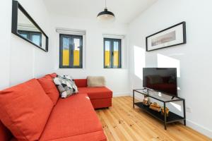 uma sala de estar com um sofá vermelho e uma televisão em Belém Design Apartments by Homing em Lisboa