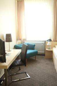 ヒルデスハイムにあるバーガーマイスターカペルのベッド、デスク、ソファが備わるホテルルームです。
