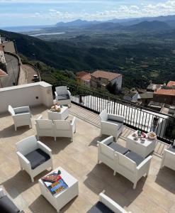 un patio con sedie bianche e tavoli sul balcone di Window on the Ogliastra apartment in Baunei a Baunei