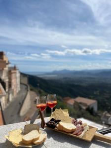 un tavolo con un piatto di cibo e due bicchieri di vino di Window on the Ogliastra apartment in Baunei a Baunei