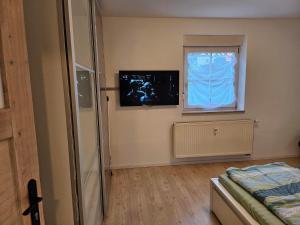 1 dormitorio con ventana y TV en la pared en Apartment Home 2, en Schwabach