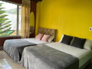 two beds in a room with a yellow wall at Holiday House - 3 Bedroom 3 Bathroom in Baños +20 photos