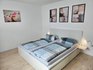 Cama en habitación blanca con cuadros en la pared en Apartment Home 2, en Schwabach