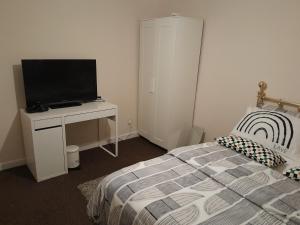 a bedroom with a bed and a desk with a television at Residence Solitaire in Woodley
