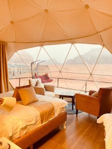 a room with two beds and a large window at Faisal Wadi Rum camp in Wadi Rum