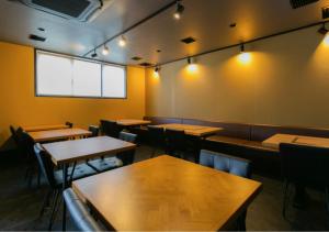 un restaurant avec des tables en bois, des chaises et des lumières dans l'établissement Residence Saku, à Osaka