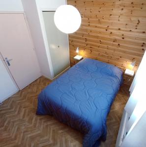 ein Schlafzimmer mit einem blauen Bett und einer Holzwand in der Unterkunft Apartment T2 sleeping corner 45 places beautiful view with balcony in Embrun