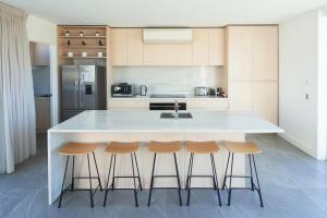 a kitchen with a large white island with bar stools at Luxury Lakeview Apartment - Lake Tekapo in Lake Tekapo