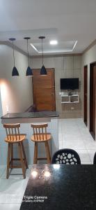 Eine Küche mit zwei Stühlen und einer Theke mit einem Fernseher in der Unterkunft Recanto do Mar em Peroba 02 in Maragogi + 19 Fotos