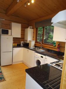 una cocina con electrodomésticos blancos en una cabaña de madera en Avonvale Holiday Lodges, en Evesham