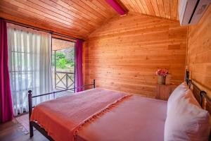 a bedroom with a bed in a wooden room with a window at Izgen Bungalows in Cıralı