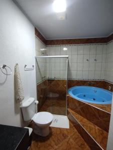 a bathroom with a toilet and a tub at Pousada Por Do Sol chalés in Monte Verde