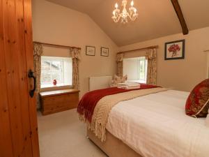 Un dormitorio con una cama grande y una lámpara de araña. en The Barn en Sedbergh