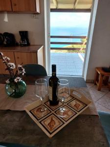 un tavolo con due bicchieri e una bottiglia di vino di Azure Horizon Apartment, Kefalonia a Angón