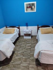 two beds in a room with a blue wall at Pasaje Hotel in Aimogasta