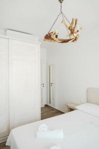 Habitación blanca con cama y lámpara de araña. en Filokalia 5 Veins - Vacation House With Sea View, en Caristo