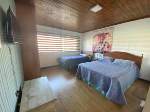 um quarto com uma cama, uma mesa e uma televisão em Habitaciones Mar Azul em El Quisco