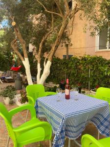a table with green chairs and a bottle of wine at Olive Tree Apartment in Sarandë