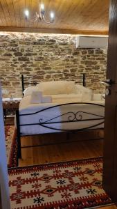 uma cama num quarto com uma parede de tijolos em Guest House Hasko em Gjirokastër