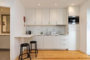 a kitchen with white cabinets and two stools at Design and bright studios near Pastéis de Belém in Lisbon