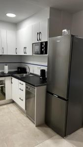 a kitchen with a stainless steel refrigerator and white cabinets at Fuengirola Paseo Marítimo 27 in Fuengirola