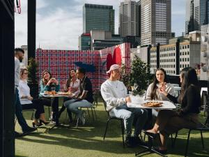 grupa ludzi siedzących przy stołach na dachu w obiekcie Pullman Melbourne City Centre w Melbourne