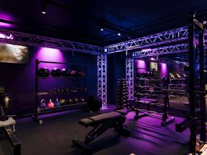un gimnasio con iluminación púrpura y un banco y pesas en Pullman Melbourne City Centre, en Melbourne