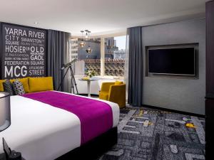 a hotel room with a bed and a tv at Pullman Melbourne City Centre in Melbourne