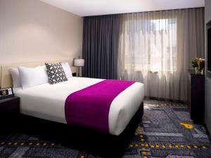 a hotel room with a large bed and a window at Pullman Melbourne City Centre in Melbourne