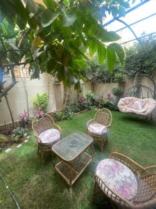 een groep stoelen en een tafel in een tuin bij Fifth Settlement Apartment in Caïro