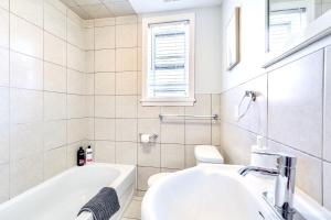 a white bathroom with a sink and a bath tub at 1BR Apartment in Corktown Hamilton in Hamilton