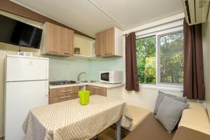 a small kitchen with a table and a white refrigerator at Mobile Homes Peškera in Pula