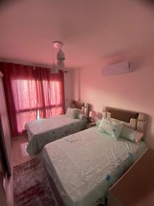 two beds in a room with pink walls and a window at شقة فندقية فاخرة لعشاق الهدوء والسكن الراقي في مدينتي in Madinaty