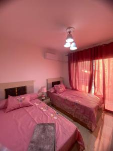 two beds in a bedroom with pink sheets at شقة فندقية فاخرة لعشاق الهدوء والسكن الراقي في مدينتي in Madinaty