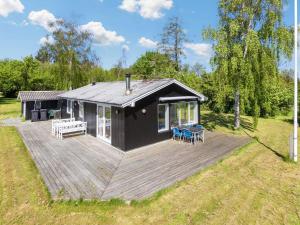 une cabine noire avec une terrasse dans un champ dans l'établissement Holiday home Nykøbing M VII, à Alsted