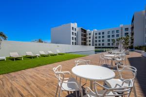 a patio with white tables and chairs on a building at Marea Los Cabos Albatros 202 in Cabo San Lucas