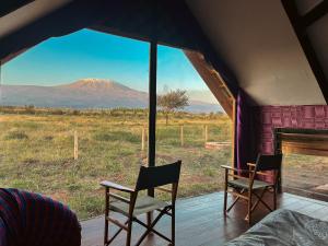 a tent with two chairs and a view of a mountain at Amboseli Glass Cabin in Kimana