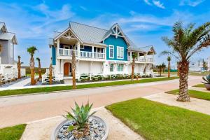 a blue and white house with palm trees at Mimosa Manor in Port Aransas