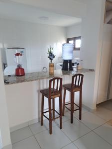 uma cozinha com duas cadeiras e um balcão com um liquidificador em Apartamento em Barra do Cunhaú em Barra do Cunhaú