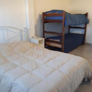 1 dormitorio con 1 cama blanca y 1 silla en Dpto Lgolf club cerca de Estadio único en Santiago del Estero