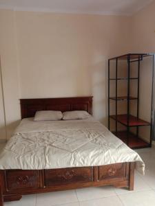 a bedroom with a wooden bed and a book shelf at Gusti family guest house in Tegalalang