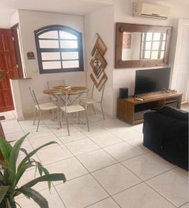 - un salon avec une table, des chaises et une télévision dans l'établissement Praiana do Luquinhas - Macumba / Pontal / RicoSurf, à Rio de Janeiro