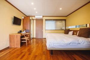 Schlafzimmer mit einem Bett, einem Schreibtisch und einem TV in der Unterkunft Shonan OVA in Yokosuka