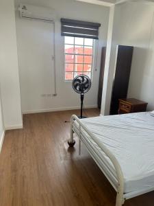 a bedroom with a bed and a window with a fan at Alice's Abode in Port-of-Spain +2 photos