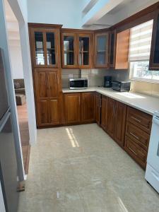 a kitchen with wooden cabinets and a tile floor at Alice's Abode in Port-of-Spain