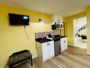 a room with a kitchen with yellow walls and a tv on the wall at Avola Mountain Lodge in Avola