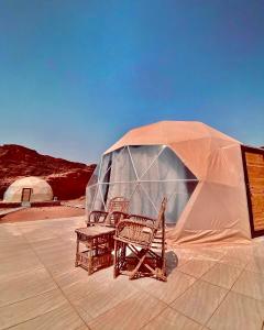 une tente avec deux chaises et une table en face de celle-ci dans l'établissement Katrina Rum camp, à Wadi Rum